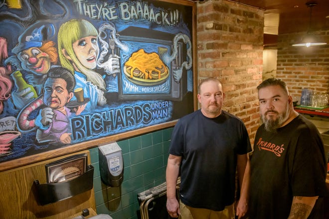 Scott Wood, left, and Raul Salazar, owners of the new Richard's Under Main, stand next to chalkboard art by Devin McGlone at the newly renovated space. The pair have relaunched the once-popular underground bar on Main Street in Peoria.